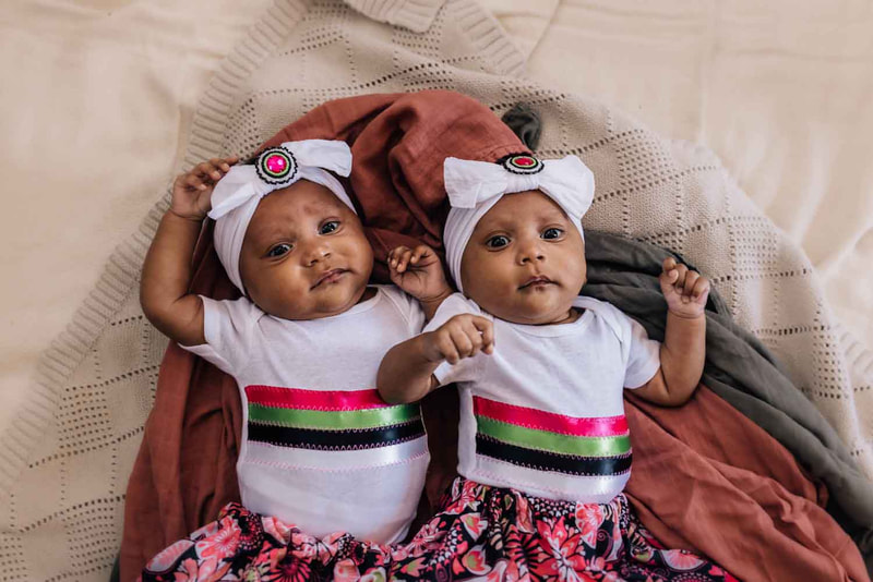 Twin baby girls dressed in native ribbon skirts.