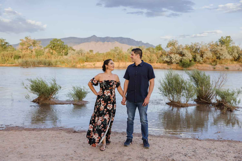 Couple hold hands in front of river.