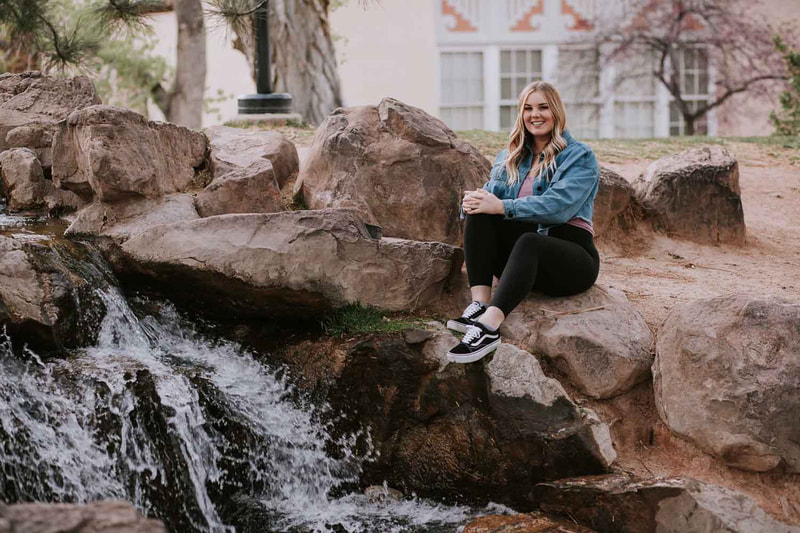 Female senior sits in front of waterfall.