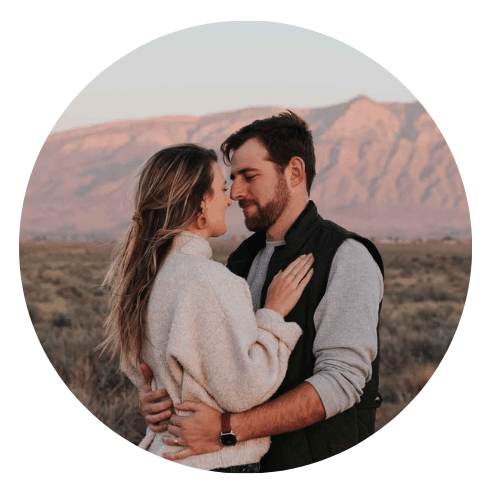 Couple gazing at eachother in front of pink Sandia mountains by Albuquerque Photographer