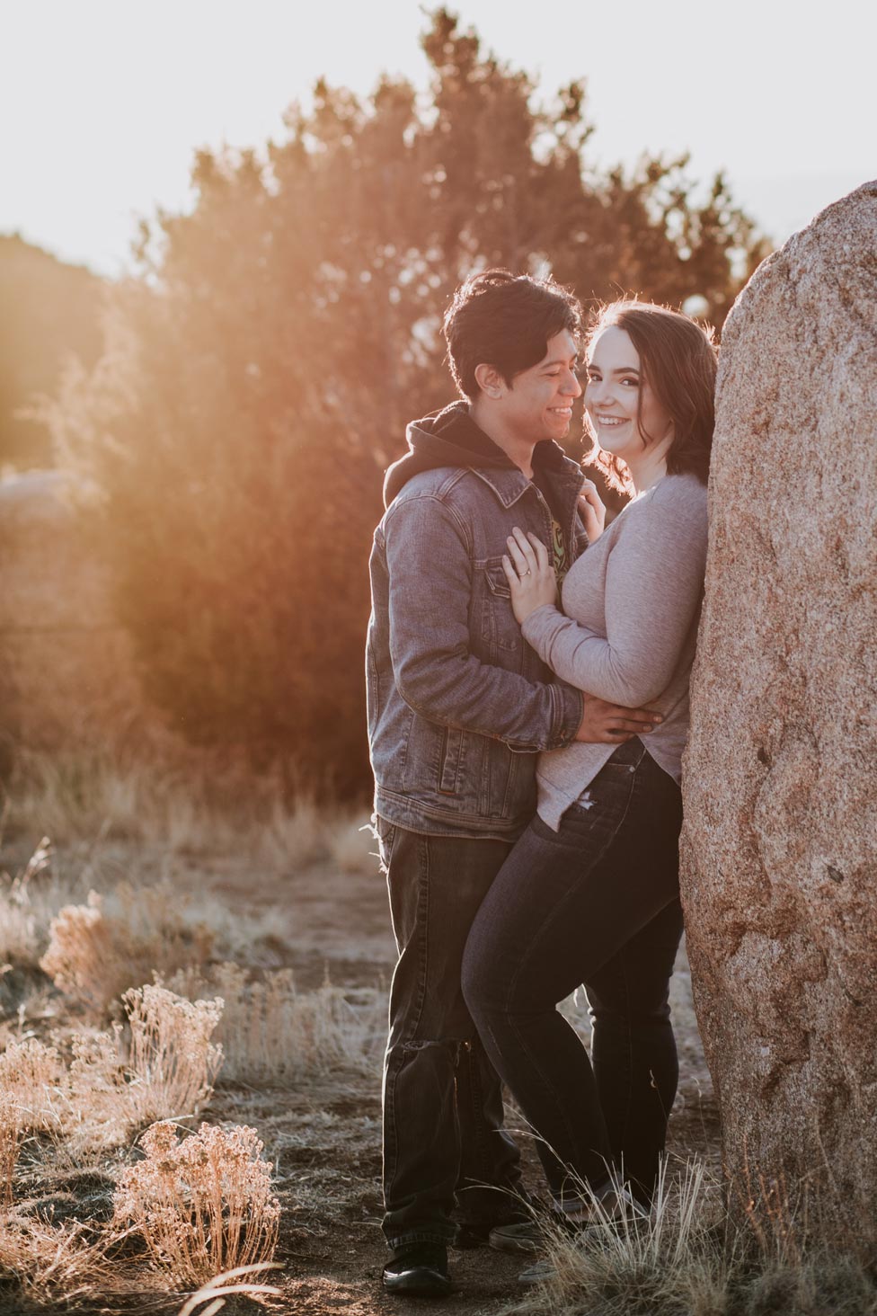 Couple in sunset leaning against rock