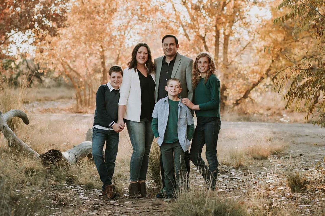 Smiling family in front of golden trees by your family photographer in Albuqerque