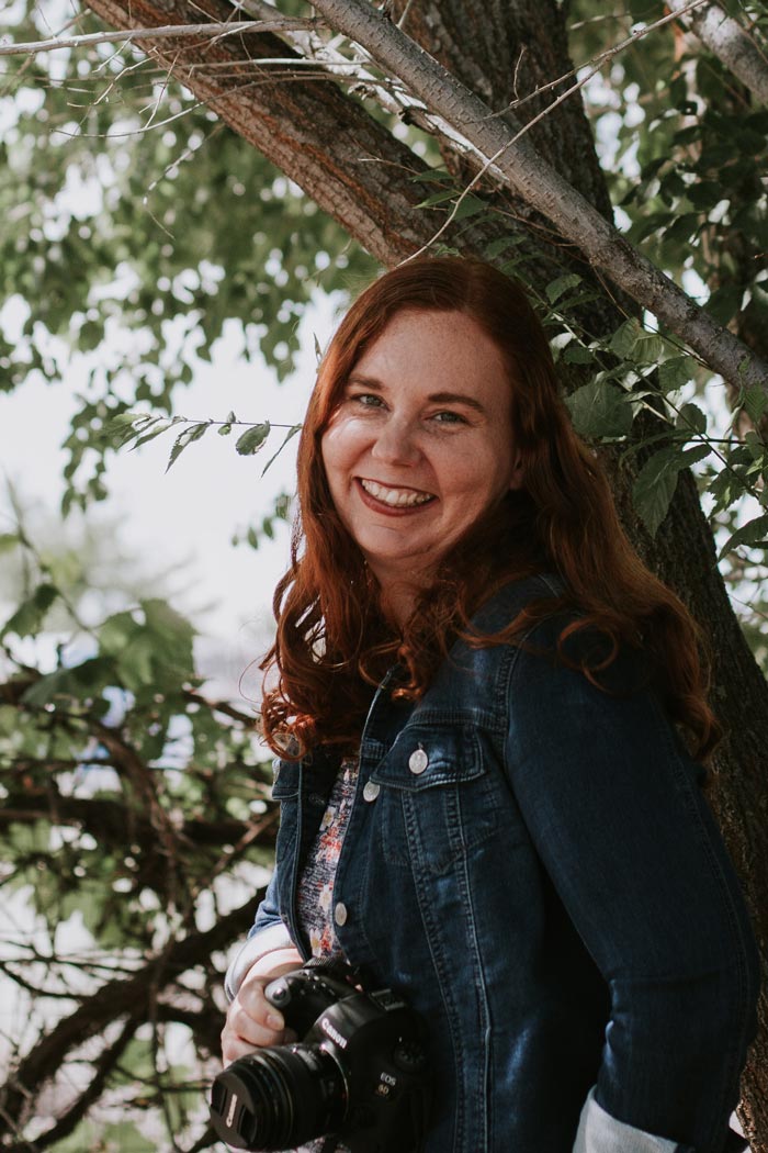 Albuquerque photographer Anna Cummings smiling under a tree with camera