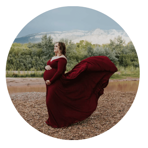 Pregnant mother in front of sandia mountains dressed in flowy red dress by Albuquerque Photographer