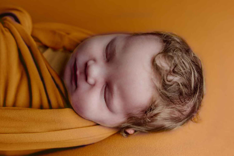 Baby sleeping wrapped in yellow on yellow blanket.
