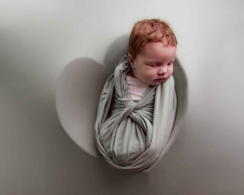 newborn wrapped in light green inside a heart shape.