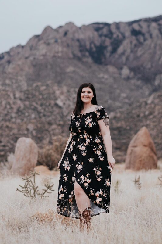 Senior photos of girl in black dress with flowers smiling